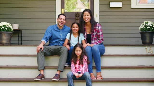 Portrait Of Family Sitting On Steps In Front Of House