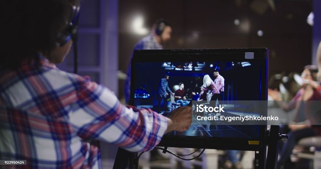 Stage director watching show in record Casual African-American woman in headset controlling process of shooting TV show standing in front of computer screen and watching record. Industry Stock Photo