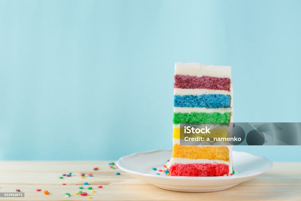 Birthday background - striped rainbow cake with white frosting Birthday background - striped rainbow cake with white frosting decorations, copy space Rainbow Cake Stock Photo