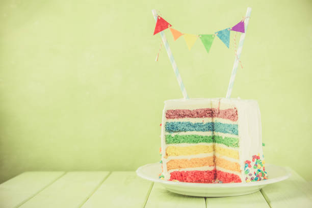 istock Birthday background - striped rainbow cake with white frosting 922953942