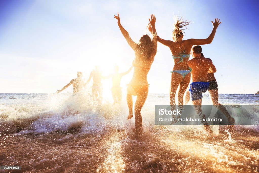 Happy friends at sunset sea beach Big crowd of friends having fun at sunset sea beach. Beach vacations concept Beach Stock Photo