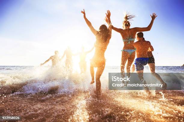 Happy Friends At Sunset Sea Beach Stock Photo - Download Image Now - Beach, Friendship, Swimming