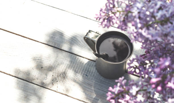 istock A metal mug with coffee and lilac branches on a wooden table 922970134
