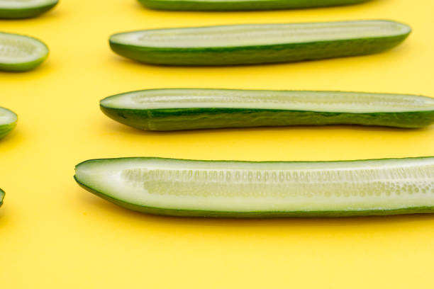 istock cut in half lengthwise cucumbers spread along on a yellow background 922973726