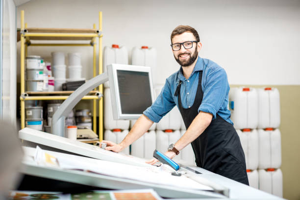 Portrait of a male worker at the printing manufacturing Portrait of a male worker standing near the operating desk of the printing manufacturing digital printing house stock pictures, royalty-free photos & images