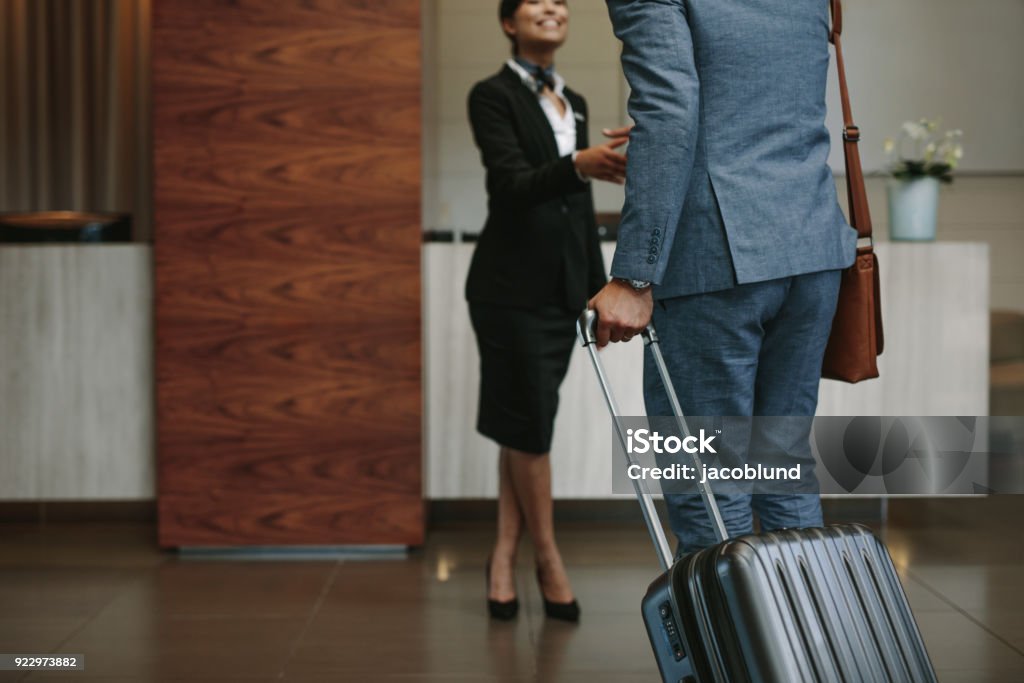 Concierge welcoming guest at hotel lobby Female concierge welcoming business man at hotel lobby. Receptionist greeting guest at hotel hallway. Hotel Stock Photo