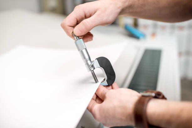 Measuring thickness of the paper sheet with micrometer Man measuring thickness of the paper sheet with micrometer at the printing plant micron stock pictures, royalty-free photos & images