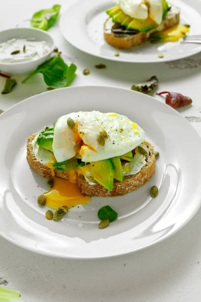 istock Sandwich, toast with avocado, soft cheese and poached egg on white background 922992888