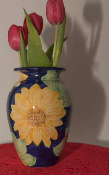 tulipani rossi in vaso in ceramica blu di vietri sul mare su doily all'uncinetto rosso e clessidra con sabbia. - 6184 foto e immagini stock