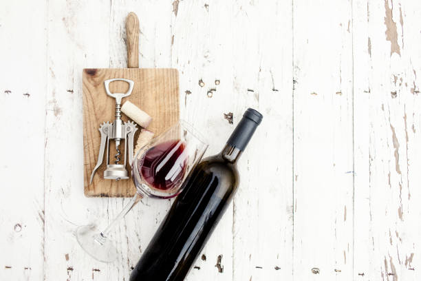 a glass of red wine, bottle, corkscrew  and wine corks on rustic board over  white wooden table, copyspsce. wine tasting concept"n - wine bottle wine wood bottle stopper imagens e fotografias de stock