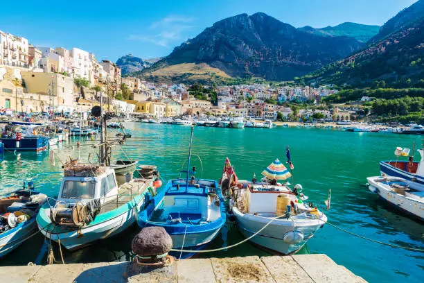 Fishing port with old wooden fishing boats docked at the marina in summer in Castellammare del Golfo in Sicily, Italy