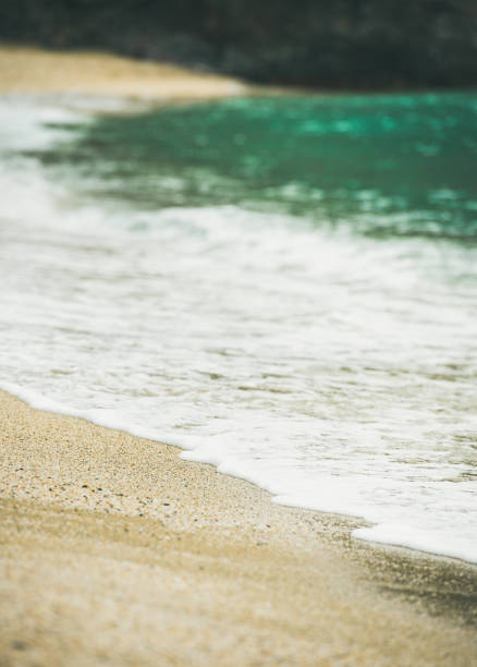 Blue sea water and sandy beach with rock at background, selective focus. Kleopatra beach, Alanya, Turkey.