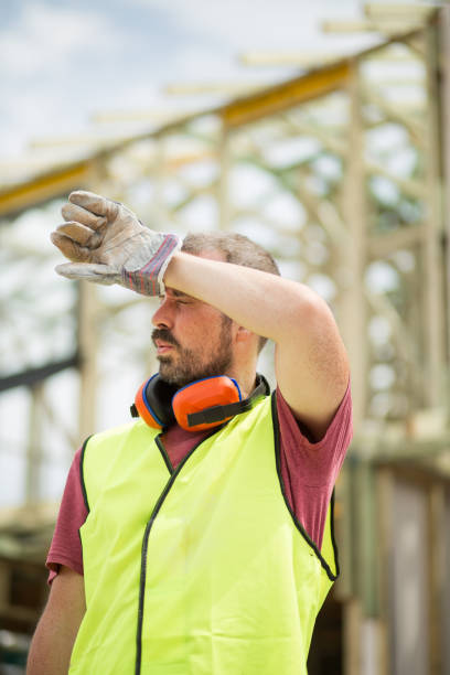 capataz de construção limpa sua sobrancelha no calor do verão australiano no canteiro de obras - mid adult men portrait hat human face - fotografias e filmes do acervo