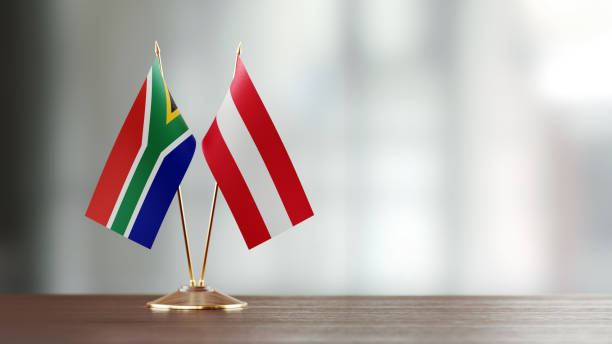 istock Austrian And South African Flag Pair On A Desk Over Defocused Background 923024522