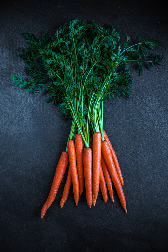 Un manojo de zanahorias. Zanahorias crudas frescas sin tallo. Jardín de zanahorias sobre un fondo negro 