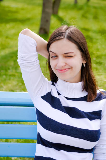 istock Beautiful brinette girl sitting on a bench, dreaming and writing her plans in a notebook, relaxing in a park on a sunny spring day 923027174