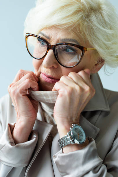 istock senior lady in trench coat and eyeglasses 923027238