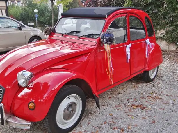 A special eye-catcher: A bright red "ugly duck" as a wedding car. Top renovated, shiny and decorated with flowers and bows, the car is waiting for the bridal couple.