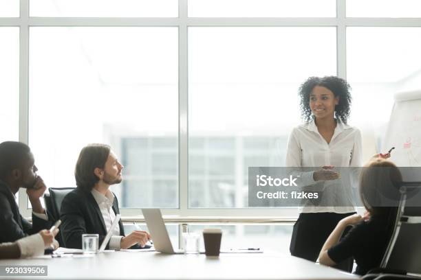 African Businesswoman Giving Presentation Working With Flipchart In Meeting Room Stock Photo - Download Image Now