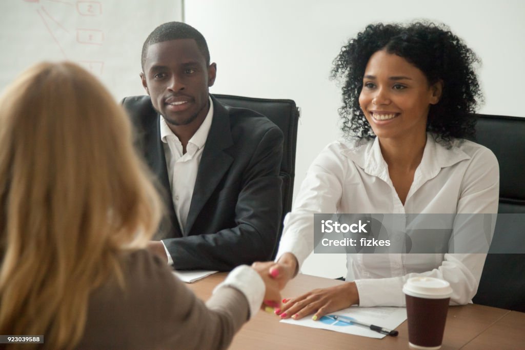 African american hr team welcoming female applicant at job interview African american hr team welcoming female applicant at job interview, diverse businesswomen shaking hands at multi ethnic group meeting, handshaking and good first impression, teamwork introduction Job Interview Stock Photo
