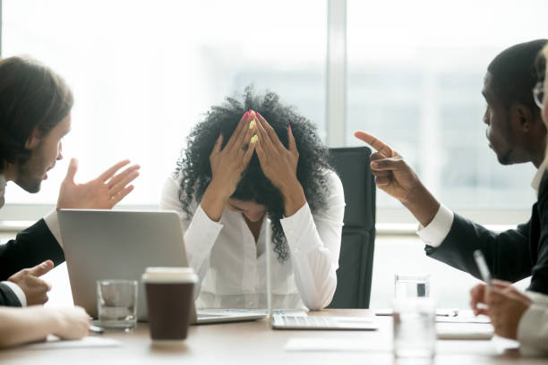 Depressed black woman leader suffering from gender discrimination at work Upset depressed black woman leader suffering from gender discrimination inequality at work, diverse men colleagues pointing fingers scolding bullying frustrated african businesswoman at workplace discrimination stock pictures, royalty-free photos & images