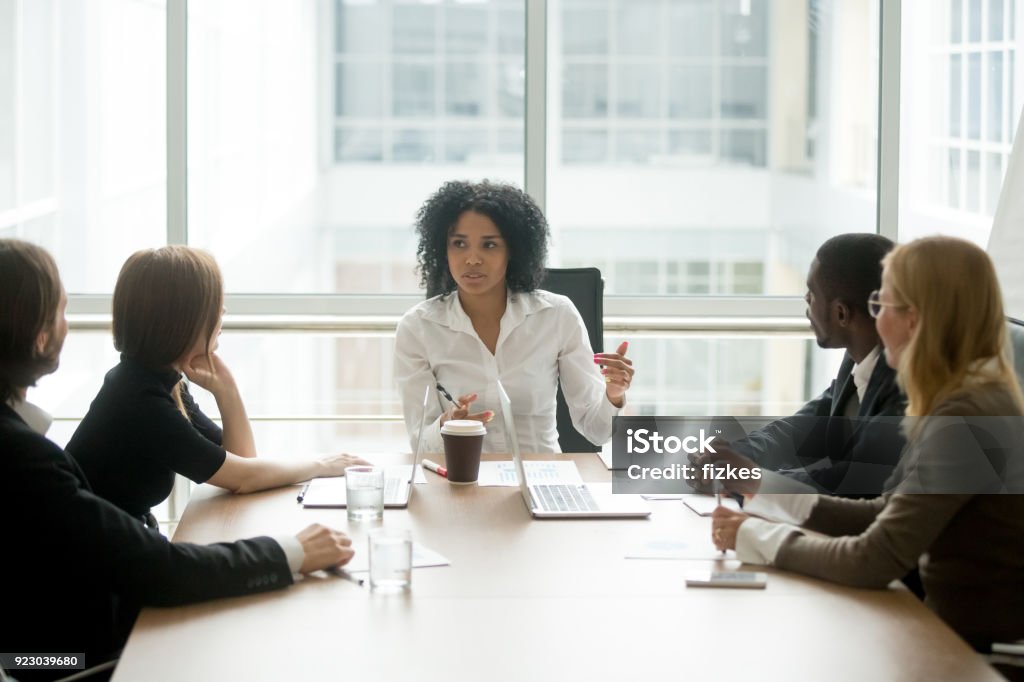 Black female boss leading corporate meeting talking to diverse businesspeople Black female boss leading corporate multiracial team meeting talking to diverse businesspeople, african american woman executive discussing project plan at group multi-ethnic briefing in boardroom Leadership Stock Photo