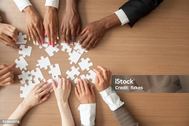Hands Of Multiethnic Business Team Assembling Jigsaw Puzzle Top View Stock Photo - Download Image Now