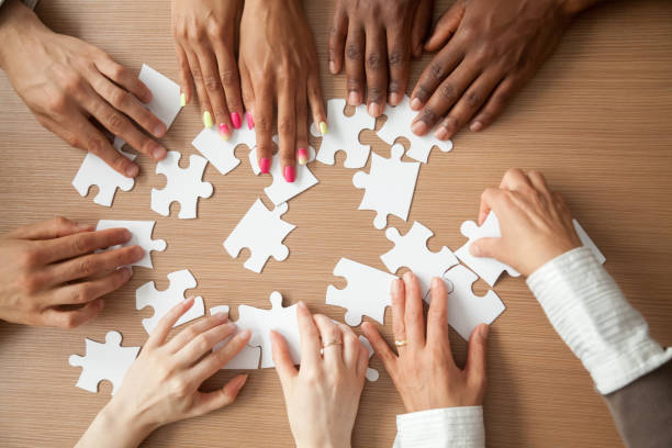 istock Hands of diverse people assembling jigsaw puzzle together, top view 923040470