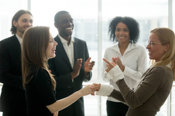 istock Smiling businesswomen holding hands celebrating success while diverse team applauding 923040486