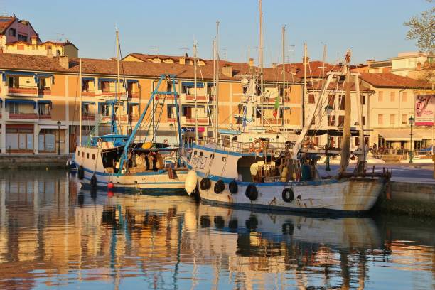 Grado, Italy - March 28, 2017: The old harbor of Grado with fishing boats and surrounding buildings in sunset light.  Northeast Italy, Europe.