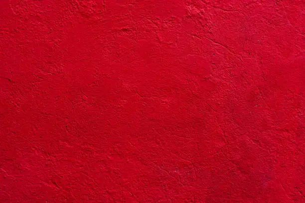 Photo of Background of a red stucco coated and painted exterior, rough cast of cement and concrete wall texture, decorative coating