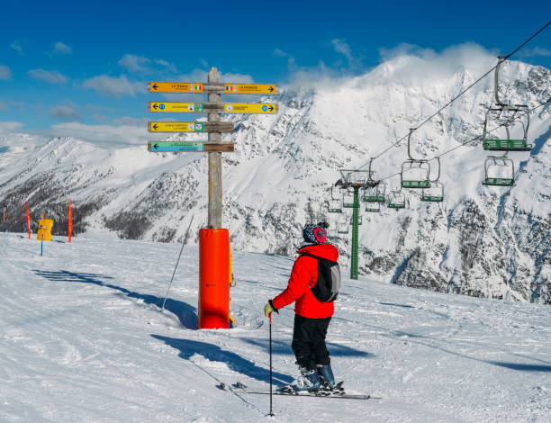 skier looking at signpost in the ski resort of la thuile, pointing towards different pistes including to the french resort of la rosiere - multidirectional imagens e fotografias de stock