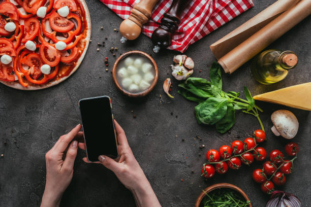 istock cropped shot of woman using smartphone while preparing pizza on concrete table 923070678