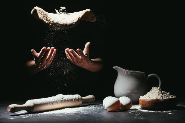 istock cropped shot of chef throwing up dough for pizza on black 923072928