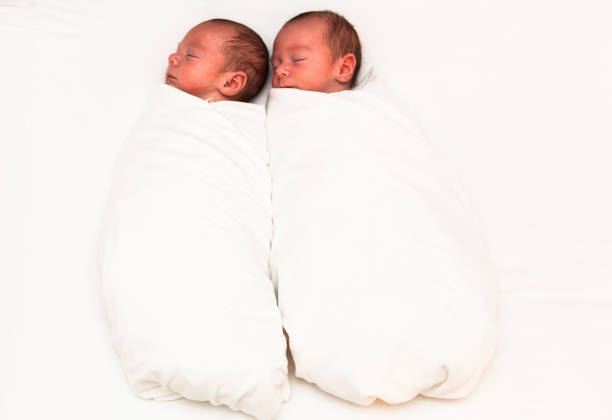 istock Identical twin baby boys sleeping side-by-side on white. 923082224