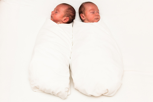 Baby boys sleeping side by side on a white background.