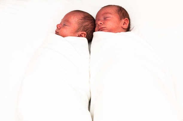 istock Identical twin baby boys sleeping side-by-side on white. 923082336