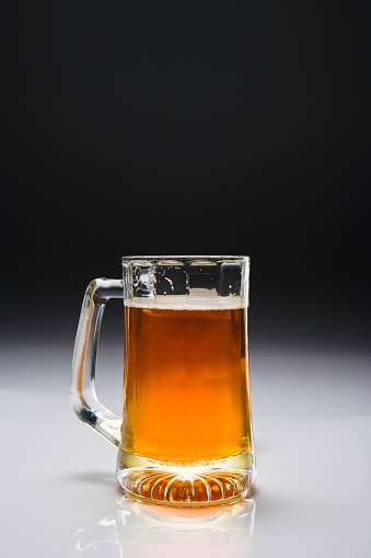 Amber beer in a glass with dark background, studio shot