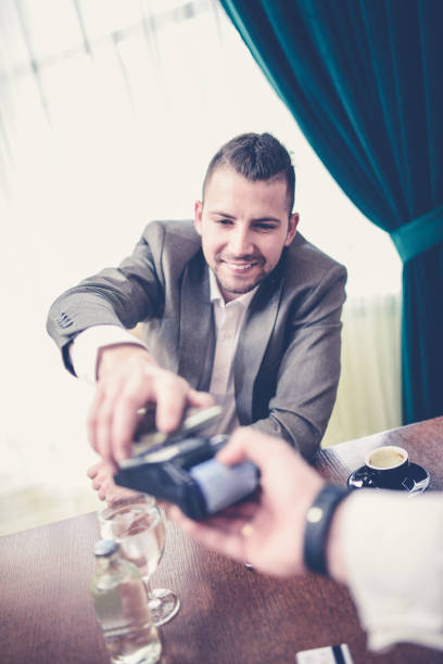 istock Smiling Businessman how Paying Bill with Mobile Phone in a Restaurant 923093246