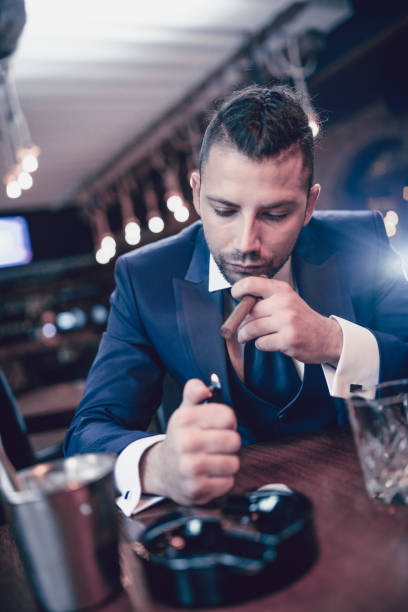 istock Businessman Lighting up a Cigar and Drinking Whisky in Restaurant 923093460