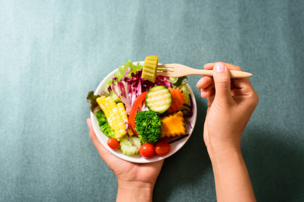 istock Hand holding wooden fork and eating salad 923096714