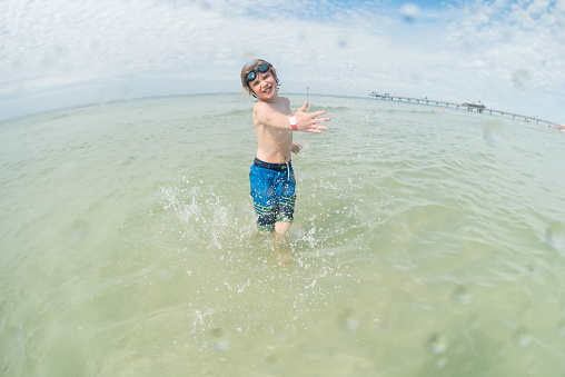 8 year old plays in the Gulf of Mexico on a beautiful evening, splashing and running in the ocean