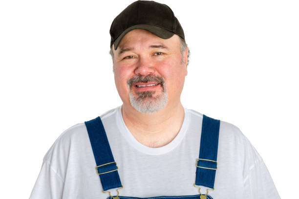 Portrait of cheerful man wearing cap with dungarees against white background