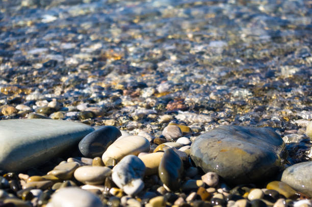 istock sea pebble beach with multicoloured stones, waves with foam 923110362