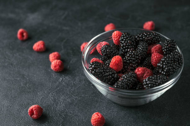 istock Glass plate with ripe red blackberries and raspberries on a black surface. 923113782