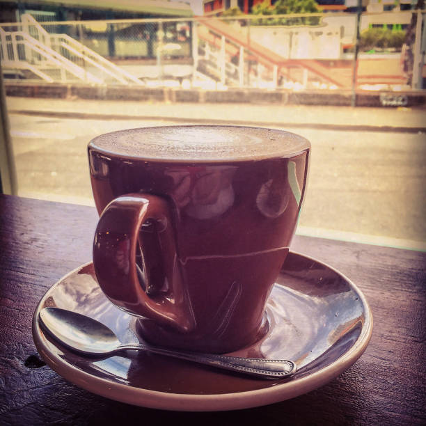 Coffee Moments: flat white espresso coffee cup with urban view of suburban railway station through cafe window
