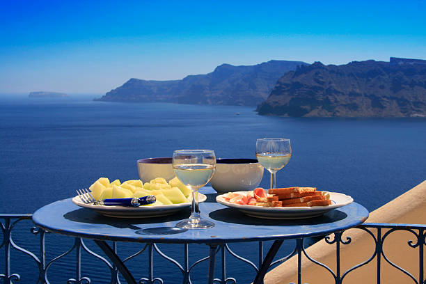 Oia, Santorini, Greece - July 3 2021: Tables on the restaurant terrace with a picturesque view of the sunset in Oia,  Santorini, Greece.