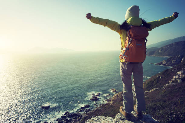 istock successful female hiker stand on sunrise seaside mountain cliff edge 923133158