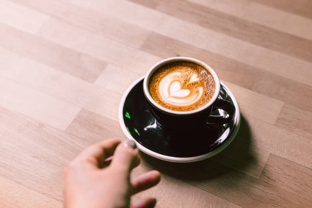 Woman's hand reaching coffee on a black plate