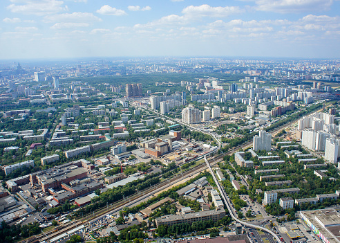 Top view of big city in the summer. Urban panorama of cityscape and blue sky, groups of buildings.
